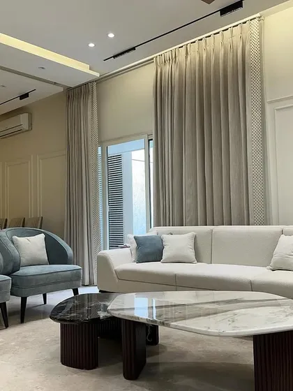 The addition of plush blue accent chairs introduces a gentle touch of color to the neutral palette, enhancing the room's sophisticated character.