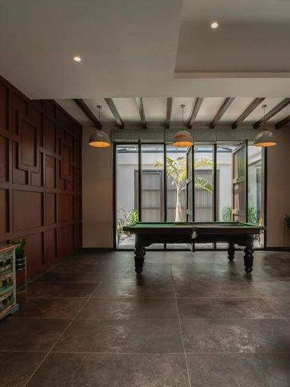 A rustic-themed game room featuring a pool table as the centerpiece. The room is paneled in rich, dark wood, creating a classic and warm atmosphere perfect for leisure and entertainment.