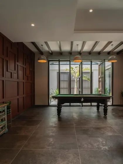 A rustic-themed game room featuring a pool table as the centerpiece. The room is paneled in rich, dark wood, creating a classic and warm atmosphere perfect for leisure and entertainment.