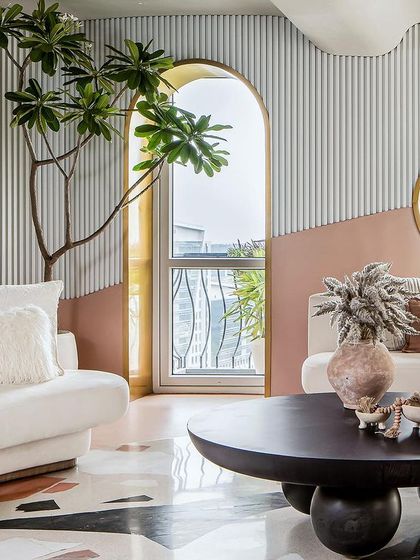 The living room is the heart of the home, with arched windows and a circular mirror reflecting the greenery outside.