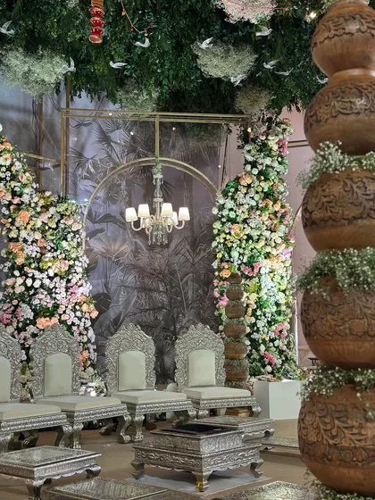 A view of the regal silver seating, set against a backdrop of cascading flowers and a custom-printed tropical mural. The mix of elements creates a unique, sophisticated look.