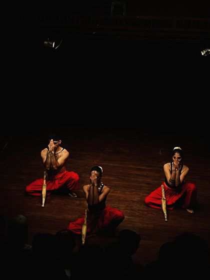 Three artists hold a pose with their wooden weapons, showcasing the discipline and artistry of their Kalaripayattu practice.