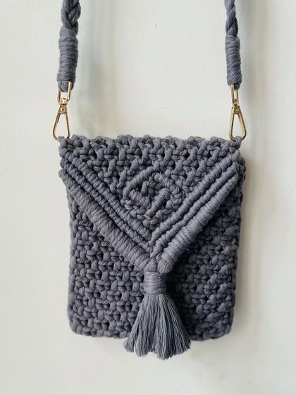 A full view of the grey mobile sling. The braided strap is strong and comfortable, and the compact size makes it perfect for when you don't want to carry a big bag.