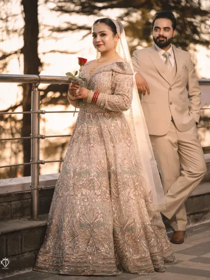 A classic portrait of the couple, with the bride holding a single red rose. The setting sun over the hills adds a touch of romance to this elegant reception look.
