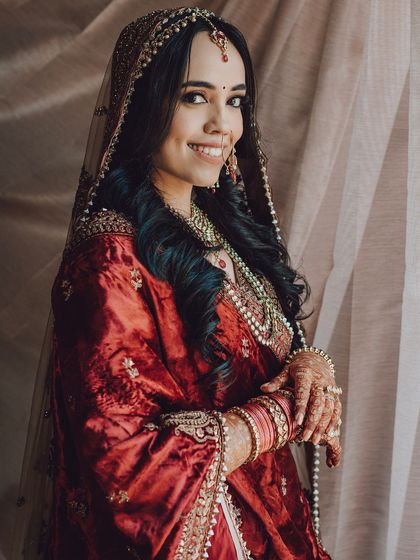 A beautiful portrait of the bride by a window, the soft light highlighting her features and traditional attire.