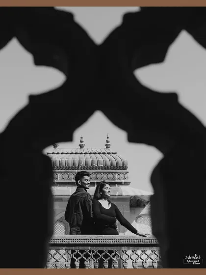 Using architectural elements to create a unique frame. This black and white shot from Vijay Vilas Palace uses the silhouette of a jali archway to frame the couple, adding depth and a sense of timeless elegance.