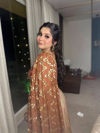 A playful glance over the shoulder. This hairstyle features a stylish curly ponytail, perfect for dancing the night away at a Sangeet.