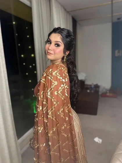 A playful glance over the shoulder. This hairstyle features a stylish curly ponytail, perfect for dancing the night away at a Sangeet.