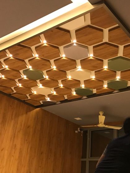 The custom ceiling in the clinic is a major design feature, with a mix of wood, colored, and lit panels creating a honeycomb effect.