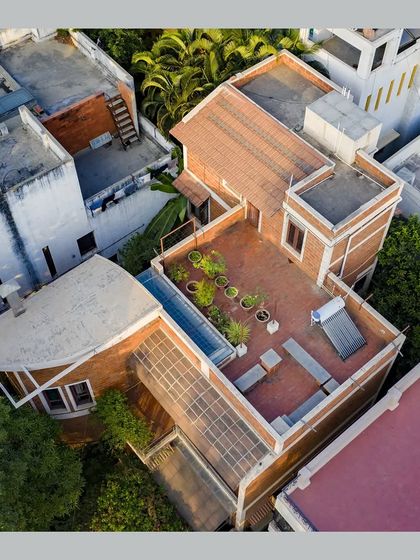 An aerial view of the roof, showing the combination of sloping Mangalore tiles, a flat terrace garden, and a solar water heater.