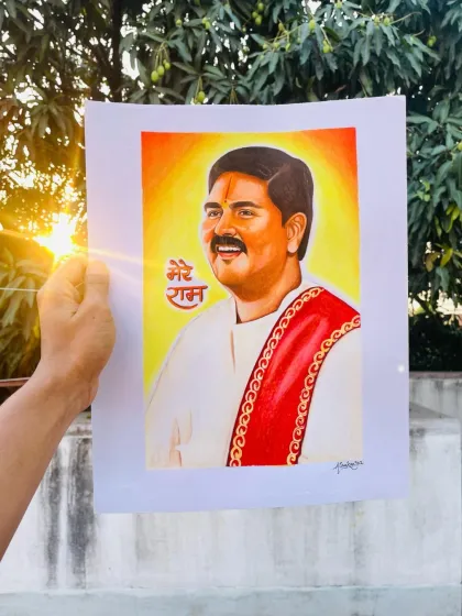 Holding up the finished portrait of Pujya Rajan Ji against the setting sun. The divine light seems to bless the artwork.
