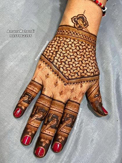 A striking back-of-hand design with a bold, leaf-filled geometric pattern. The fingers are decorated with small bird motifs, adding a delicate touch.