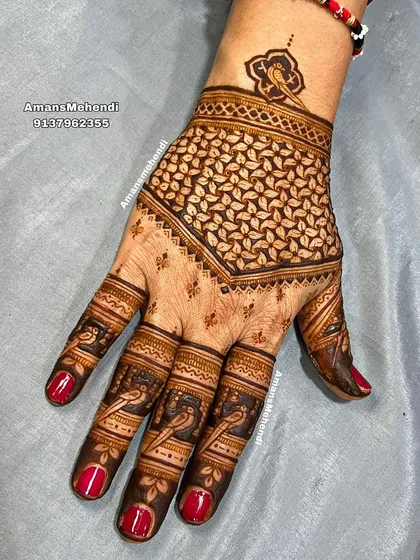 A striking back-of-hand design with a bold, leaf-filled geometric pattern. The fingers are decorated with small bird motifs, adding a delicate touch.