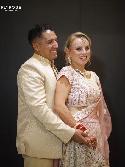 This international couple looks absolutely radiant. Her pastel pink lehenga and his cream sherwani are a beautiful combination for a day wedding.