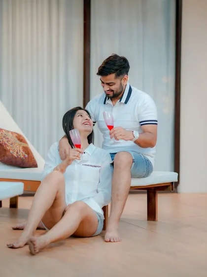 A relaxed and intimate moment at a modern resort-style location. This shot captures the couple enjoying a quiet celebration with champagne, showcasing a casual yet sophisticated pre-wedding vibe.