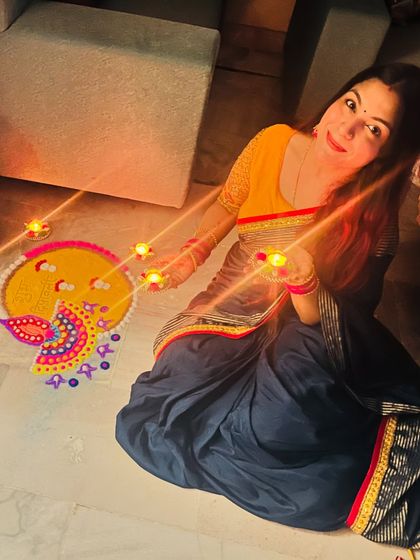 Celebrating Diwali with a handmade rangoli and diyas. I am wearing a simple yet elegant blue and yellow cotton saree, perfect for at-home festivities.