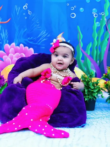 A sweet baby mermaid in a pink costume, posing in our vibrant under-the-sea world.
