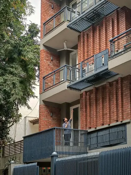 The facade of a house in Panchsheel, New Delhi, where the building's skin is crafted from exposed brick and steel. The design integrates essential services and mechanical units into the architectural expression, making them a deliberate part of the aesthetic.