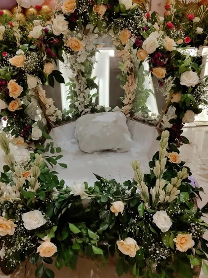 A close-up of the baby entry cart, exquisitely decorated with fresh white and peach roses and other foliage.