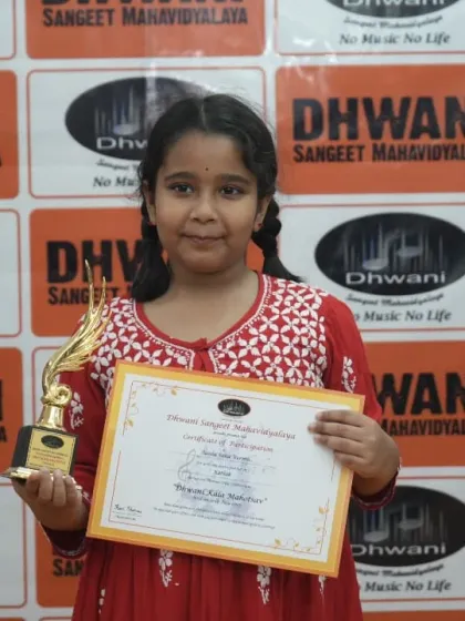A young student proudly displays her certificate and award.
