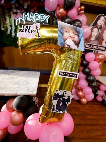 A close-up of the personalized details for a Blackpink themed party, including a custom photo on the age balloon.