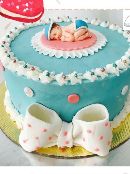A sweet sleeping baby atop a beautiful blue cake with a polka-dot bow. This design is a popular and heartwarming choice for baby showers and welcoming a new arrival.