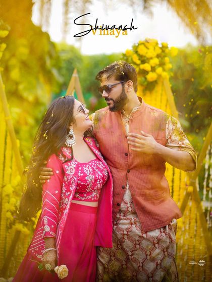 A beautiful, romantic portrait of the couple at their Haldi ceremony. The flower petals showering down on them add a touch of magic to this lovely moment.