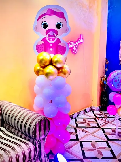 A corner decoration for a Naming Ceremony, featuring a balloon pillar with a baby girl cutout and a smaller balloon bouquet.