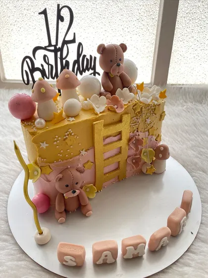 A teddy bear-themed half-cake in sunny yellow and pink. A cheerful way to celebrate being halfway to one.