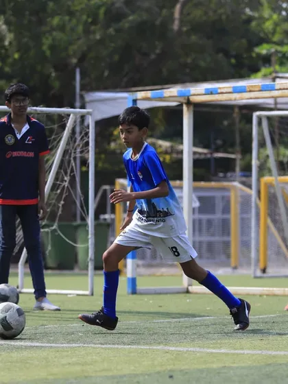 A U13 player calmly controls the ball, demonstrating composure under pressure.