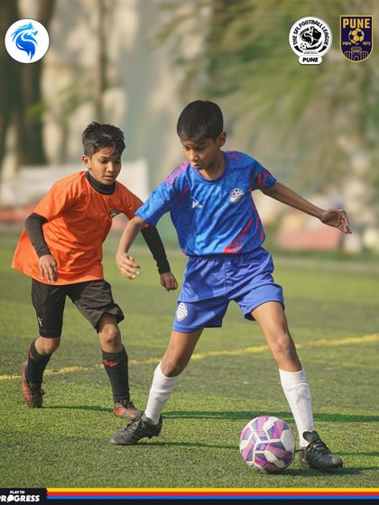 A player in Pune maintains his balance and control while under pressure from a defender.