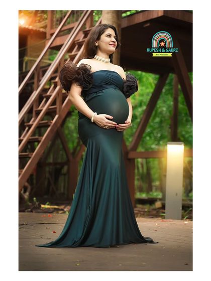 A portrait of strength and grace. The mom-to-be stands tall in a gorgeous teal gown, surrounded by the lush greenery of the park, showcasing the powerful beauty of pregnancy.