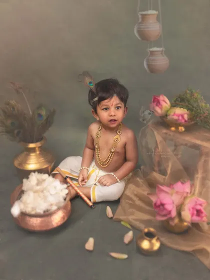 This little Krishna sits amidst a carefully arranged scene of hanging pots, peacock feathers, and fresh lotuses. Every element is placed to build a rich, visual story.