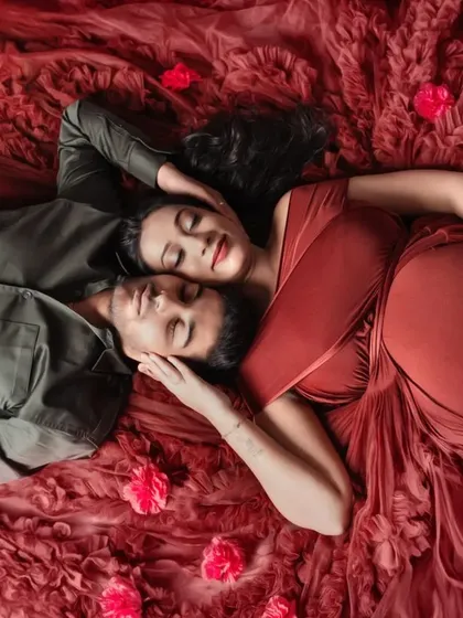An overhead shot that feels like a scene from a romance novel. Lying on a bed of red fabric, this couple shares a quiet, intimate moment before their baby arrives.