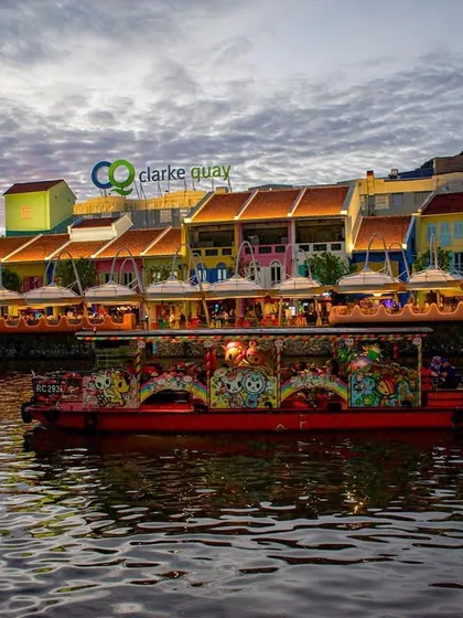 A shot of a colorful tour boat on the river at Clarke Quay, Singapore, just as the evening lights begin to turn on.