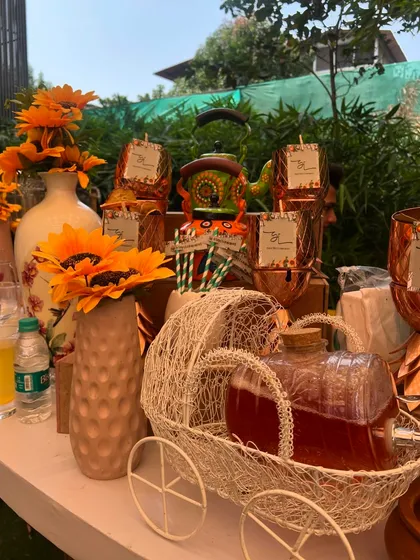 A bright and cheerful sunflower-themed setup for a daytime event, featuring decorative kettles, custom tags, and bottled juices.