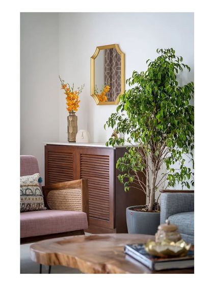 A corner of the living room featuring a pastel rose sofa and a storage unit with a brass-framed mirror. The furniture nestles between these elements, creating a cozy and well-defined seating zone.