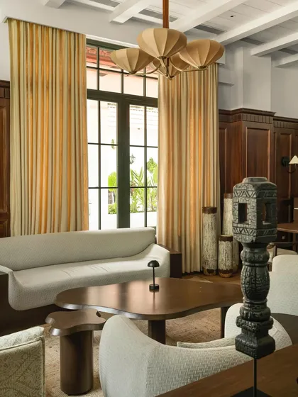 A seating arrangement in the lounge, where modern, monolithic sofas are juxtaposed with traditional wood paneling and curated artifacts.