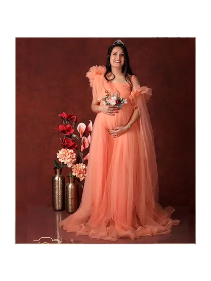 A regal portrait of the mom-to-be in a magnificent peach-colored gown, looking like a queen in our studio.