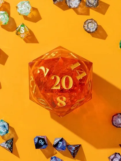 A vibrant and playful flatlay of multi-colored dice surrounding a giant D20. The bright orange background and hard shadows create a high-energy, eye-catching composition.