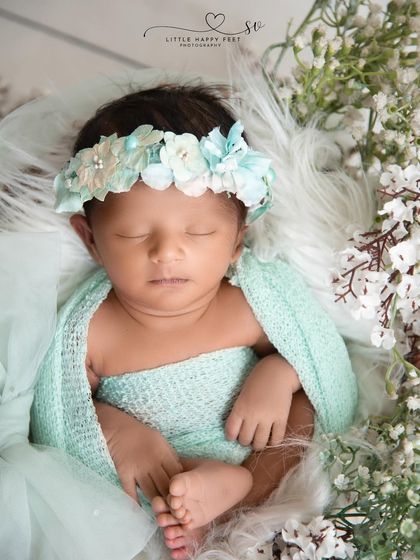 A vision in mint green. The soft green wrap and matching floral headband, surrounded by baby's breath, create a fresh and delicate portrait.