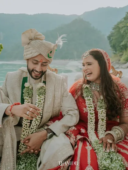 Laughter and love by the Ganga. This candid photo captures the genuine joy of the couple, with the bride's natural makeup looking fresh and beautiful throughout the ceremony.