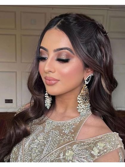 A soft and romantic party look. The client's makeup features warm, shimmery tones, and her hair is styled in classic Hollywood waves.