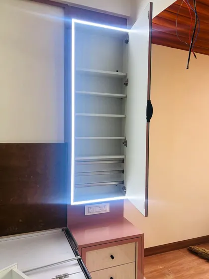 A hidden dressing cabinet with a backlit mirror. When closed, it looks like a simple part of the wardrobe, but opens to reveal organized shelving for all your essentials.