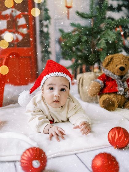 A baby's first Christmas portrait, lying on his tummy in a Santa hat. An adorable way to mark the occasion.