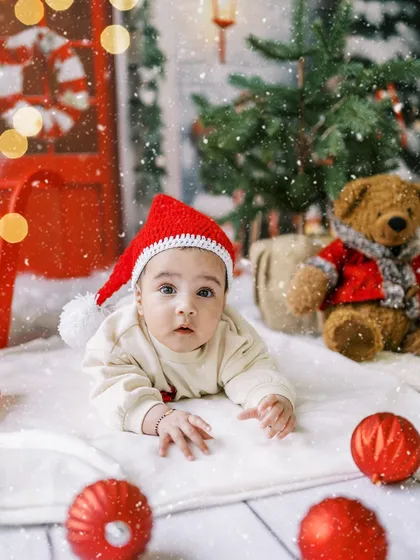 A sweet baby in a Santa hat, doing some tummy time in our snowy Christmas scene.