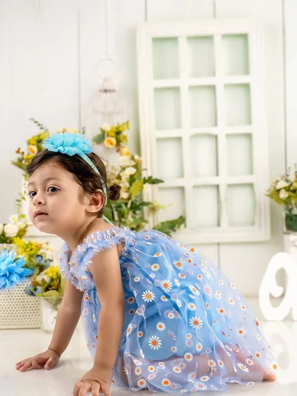 On the move. This crawling shot shows off the beautiful details of her dress and the whimsical floral studio setup for her first birthday.