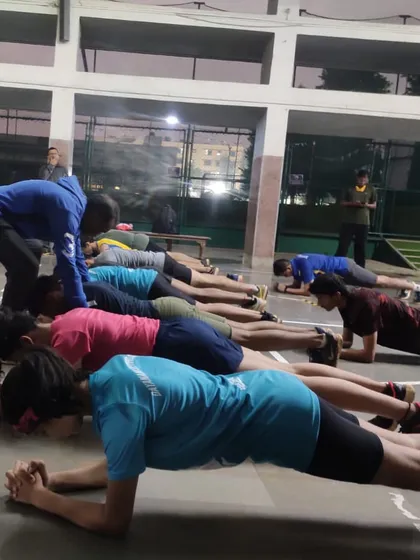 Form is everything. Here, one of our coaches is correcting an athlete's posture during a plank exercise. We focus on mastering foundational movements like this to build core strength and prevent injuries, ensuring a solid base for peak performance.