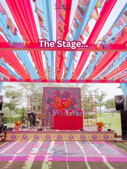 The stage for a wedding carnival, set with a colourful backdrop and ready for live music and performances. The vibrant draping overhead completes the festive look.