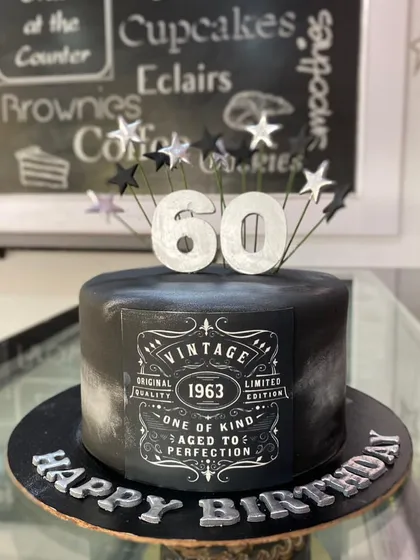 A sophisticated "Aged to Perfection" cake for a 60th birthday. The black and silver design mimics a vintage whiskey label for a classic and stylish look.